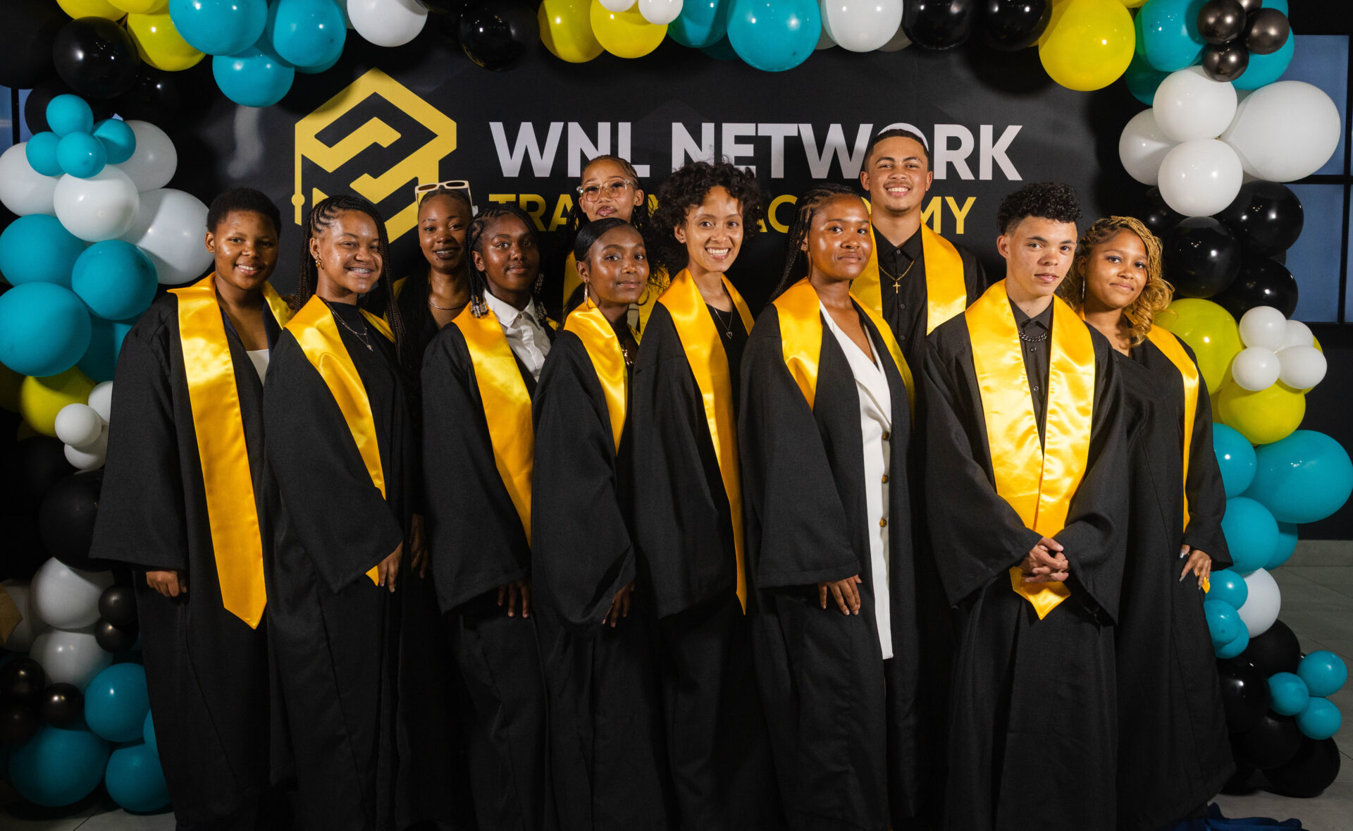 Graduates in black gowns and gold stoles celebrating